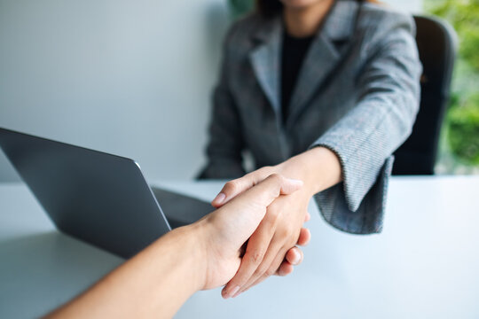 Closeup image of two businesspeople shaking hands in office