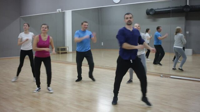 Young smiling woman practicing vigorous lindy hop movements in dance class