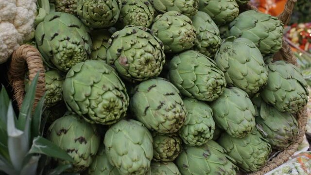 Pile of fresh young buds of artichokes on showcase of greengrocery
