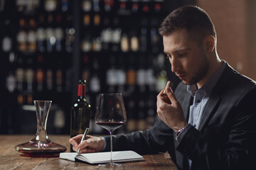 Sommeliers male tasting red wine and making notes aroma degustation card