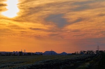 sunset with multicolored clouds in the sky in the summer field
