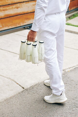 Delvery man carrying glass bottles to entrance of customer