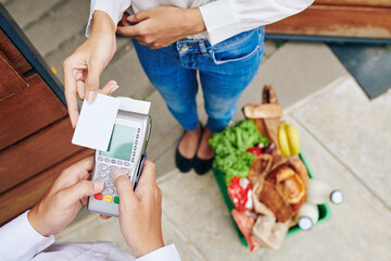 CLose-up image of female customer paying with credit card for groceries order