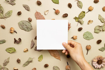 Empty memo paper with autumn dry leaves on khaki brown background. flat lay, top view, copy space