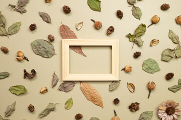 Wooden photo frame with autumn dry leaves on khaki brown background. flat lay, top view, copy space