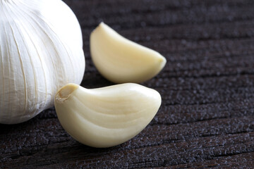 Raw garlic cloves and bulb on dark wooden background..