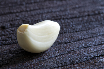 Raw garlic clove on dark wooden background..