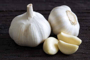 Raw Garlic Bulb and Cloves on dark wooden background..