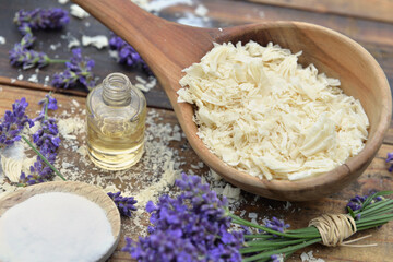 spoon full of flakes of soap with essential oil and bunch od lavender flowers and sodium bicarbonate on wooden background - obrazy, fototapety, plakaty