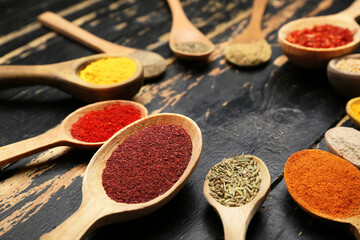 Many spoons with different spices on table