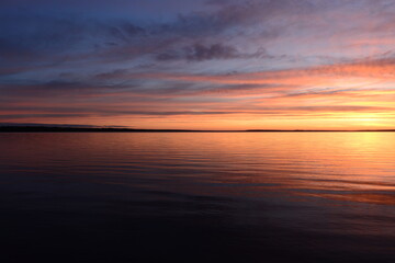 Fototapeta premium Sunset in the clouds blue sky over calm water
