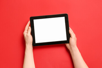 Hands with modern tablet computer on color background