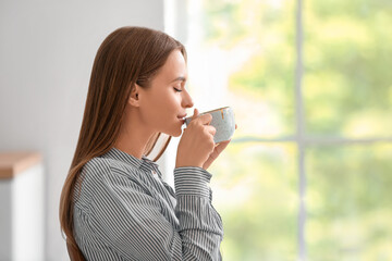 Beautiful young woman drinking tea at home