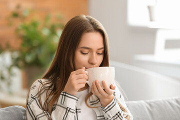 Beautiful young woman drinking tea at home