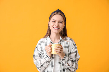 Beautiful young woman with cup of tea on color background