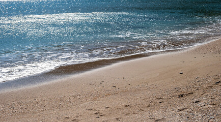 Sandy beach, ripples rolling on the coast, calm sea water background
