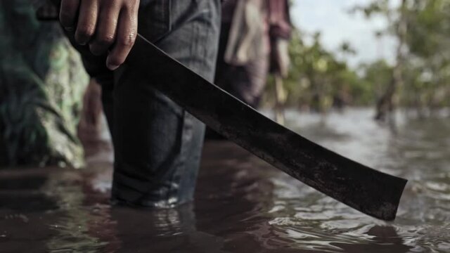 man with machete in the river forest water at rural Burma tropical area
