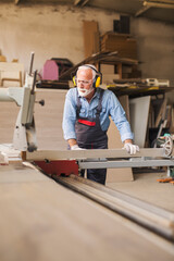 Fototapeta na wymiar Elderly carpenter using circular saw