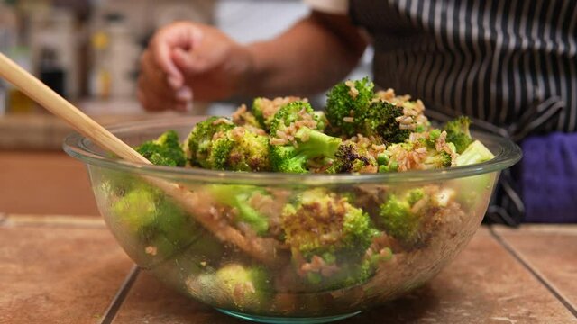 Stirring green onions or scallions into a freshy fried and steaming broccoli dish with other ingredients