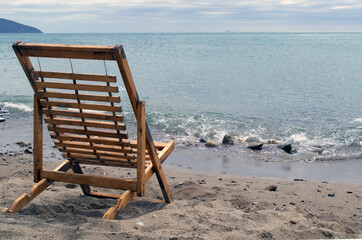 Wooden deck chair on the sandy beach with sea views. 