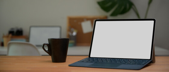 Digital tablet with keyboard and coffee mug on wooden table, clipping path.