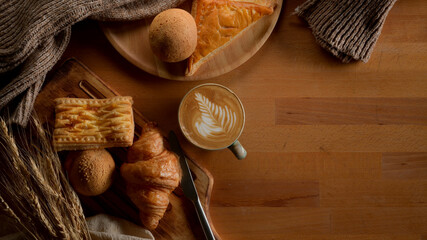 Breakfast table with freshly baked bakery, latte coffee, decorations and copy space on wooden table