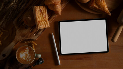 Digital tablet with clipping path on wooden table with pastries and hot latte coffee