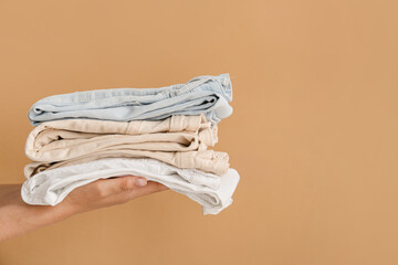 Female hands with stylish jeans pants on color background