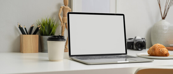 Blank screen laptop on worktable with stationery, camera and decorations, clipping path.