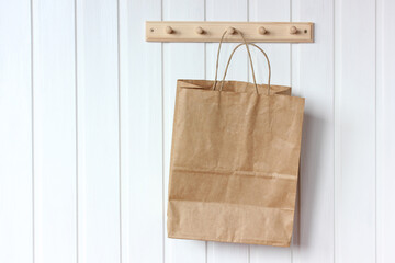 mockup, scene creator. brown paper bag hangs on a white wall.