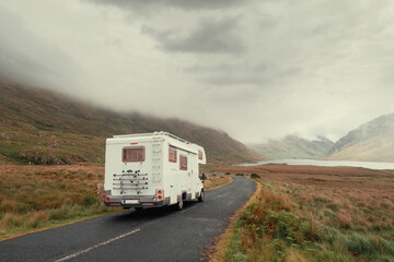 Motor home on a small asphalt road into mountains, Connemara region, Ireland, Low cloudy sky....