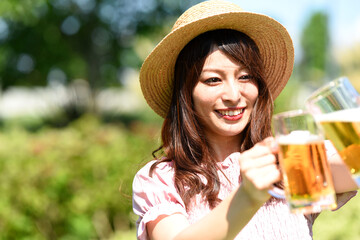 外でビールを持ちながら乾杯をする女性