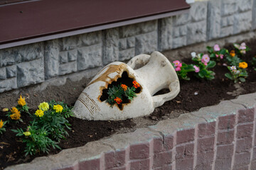 Broken amphora on a flowerbed.
