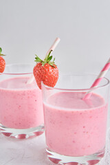 Strawberry milk shake in glass with straw and fresh berries on a white background
