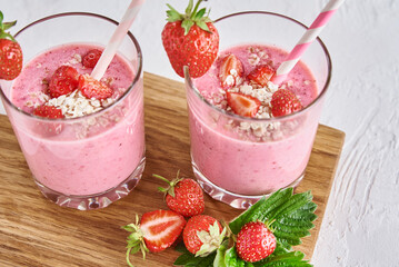 Strawberry milk shake in glass with straw and fresh berries on a white background