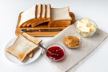 Ingredients for a delicious breakfast - toasted bread, butter, peanut butter and homemade raspberry jam on a table