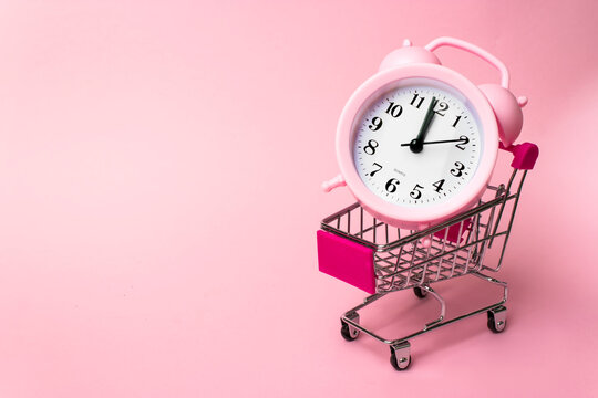 Shopping, purchases, supermarket, sale, mall concept. A metal supermarket trolley in miniature with alarm clock inside. Grocery supermarket, food and eats online buying and delivery concept.