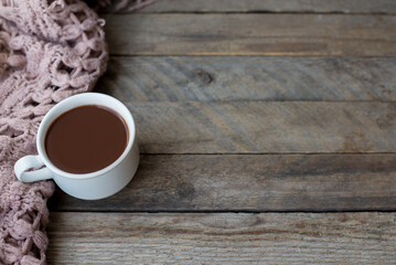 Cup of hot coffee on rustic wooden table with warm sweater , autumn or winter morning concept, copy space