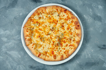 Homemade pizza 4 cheese in a white plate on a concrete background