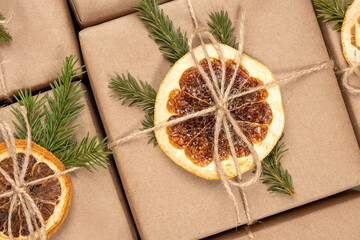 Fototapeta na wymiar Christmas or New Year's pattern from boxes in craft paper with dried oranges, spruce branches and twine close-up. Concept Zero waste, eco friendly Merry Christmas. Top view Flat lay