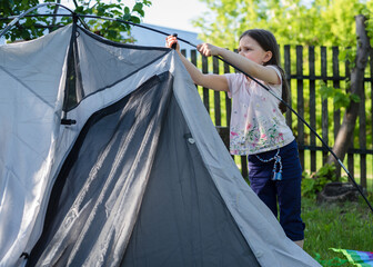 little girl with a tent in nature. Camping and outdoor recreation