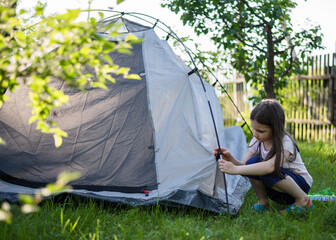 little girl with a tent in nature. Camping and outdoor recreation