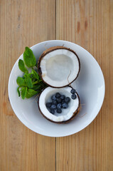 Сoconut in a plate with mint and blueberries