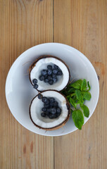 Сoconut in a plate with mint and blueberries