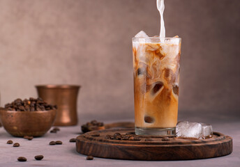 Milk pouring into the glass of iced coffee  