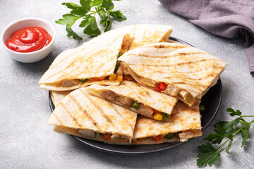 Triangular slices of a Mexican quesadilla with the sauce. The traditional dish of Mexico is tortillas stuffed with meat and vegetables. copy space.