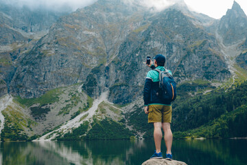 man with backpack looking at lake in mountains