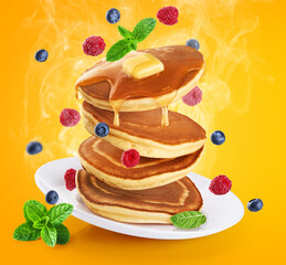 Pancakes with fresh berry and honey on yellow background. Healthy breakfast.