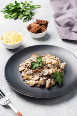 Stewed mushrooms champignons in sauce with sour cream and cheese parsley on a plate.
