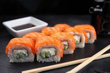 Sushi Roll Philadelphia, with cream cheese and salmon, on a black background, with a shallow depth of field